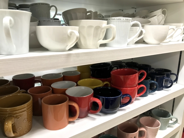 白い棚に並んだコーヒーカップ、マグカップ、カトラリー